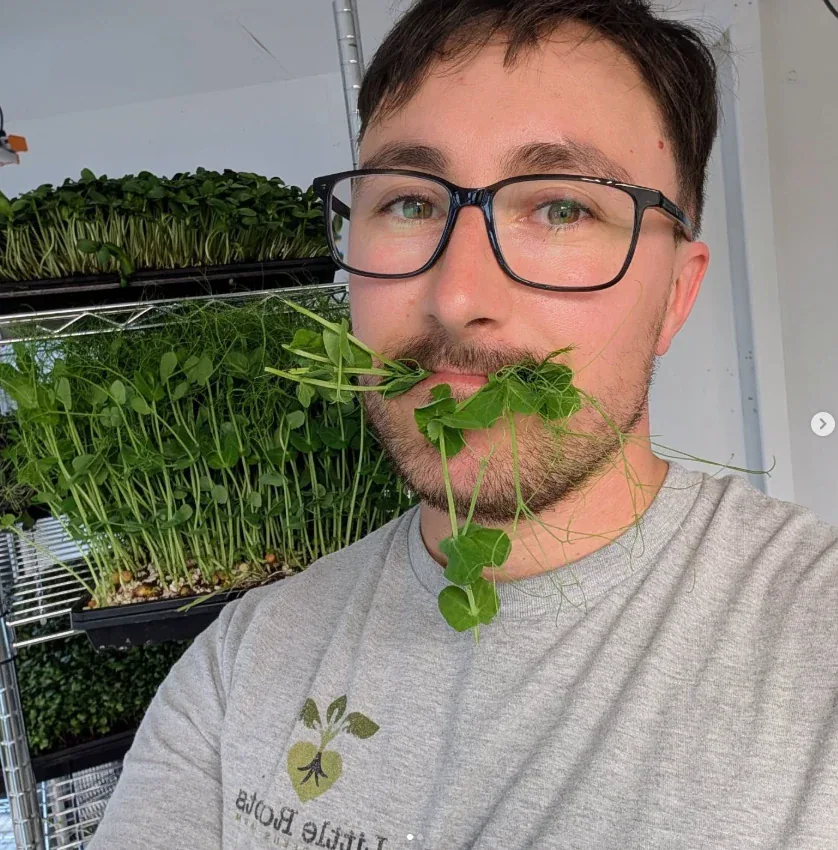 Amery, owner of Little Roots Farm, beside trays of microgreens
